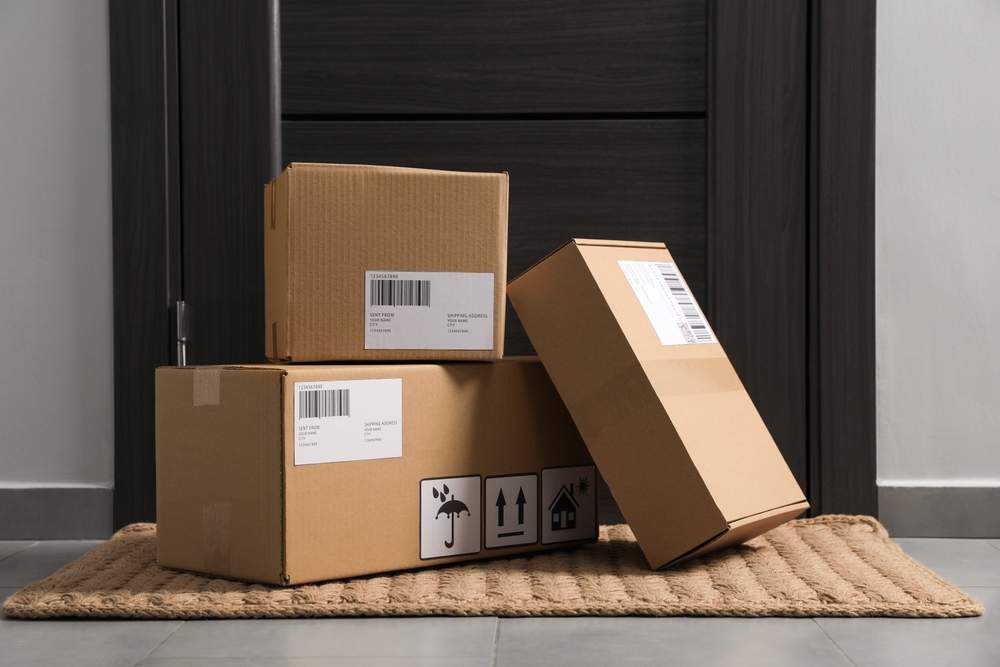 Cardboard boxes on floor mat near entrance. Parcel delivery service.